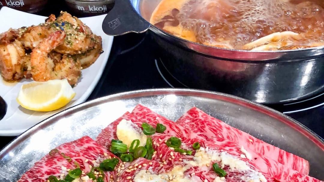 Marbled beef with green onion and sesame, fried shrimp and a bubbling broth pot at Mokkoji