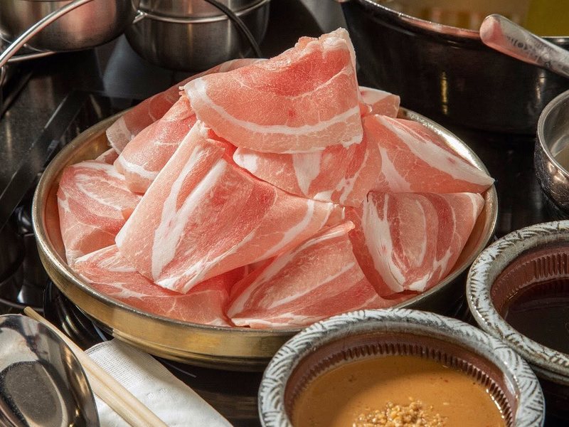 Thin-sliced pork beside bowls of Mokkoji's dipping sauces